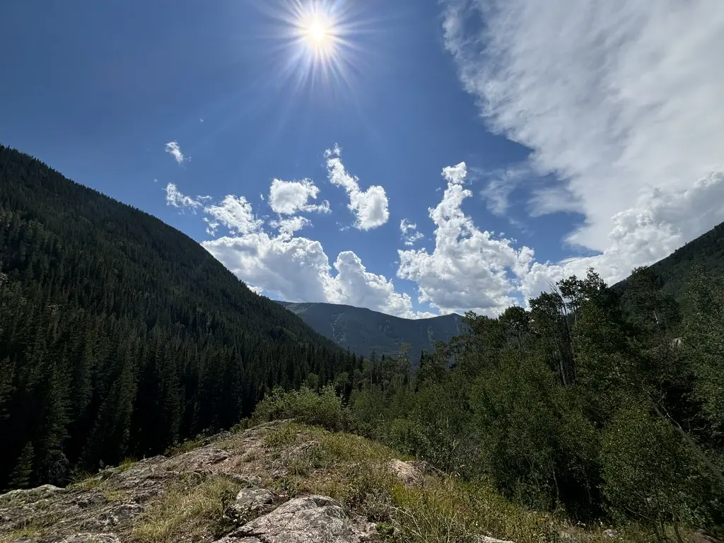A sunlit trail overlooking a Colorado mountain valley